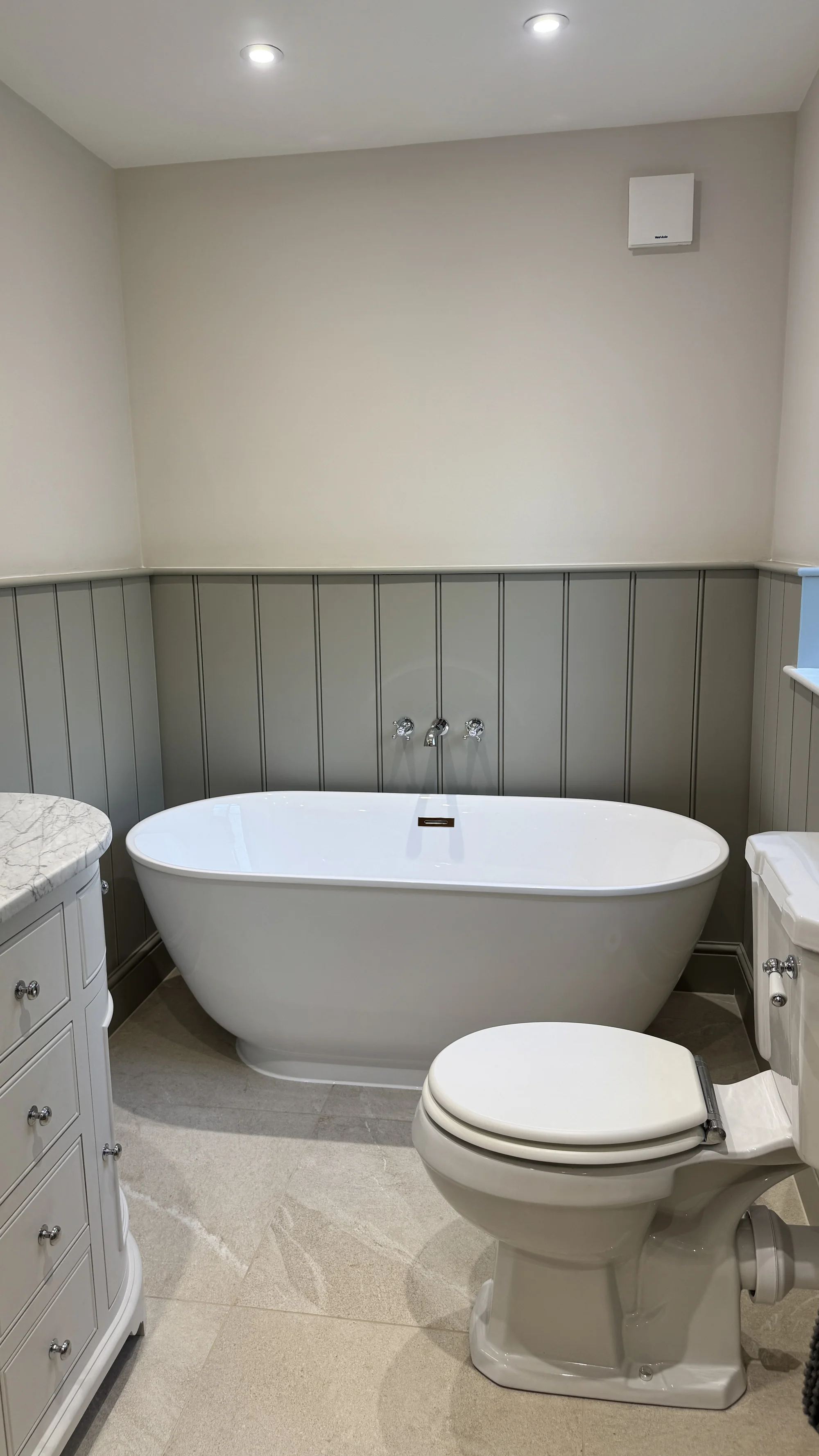 Freestanding bath and traditional WC against sage panelling