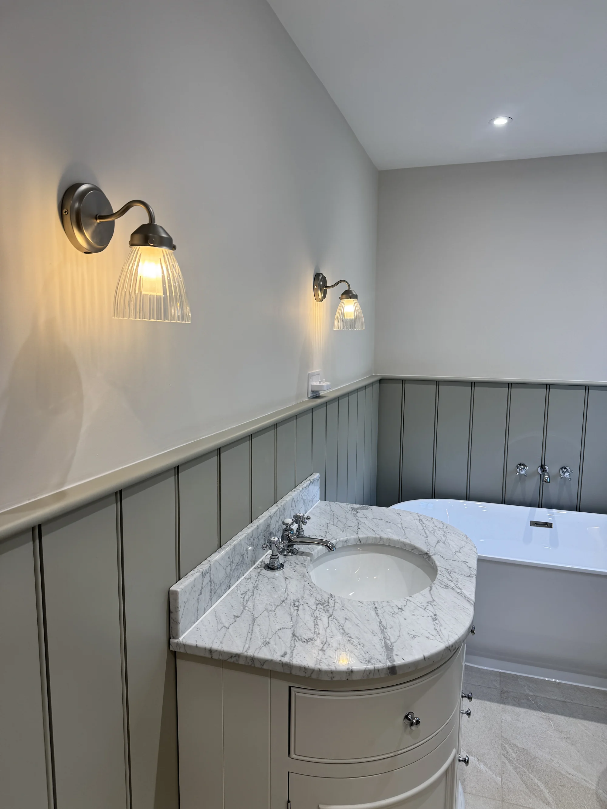 Marble-topped vanity beside the freestanding bath
