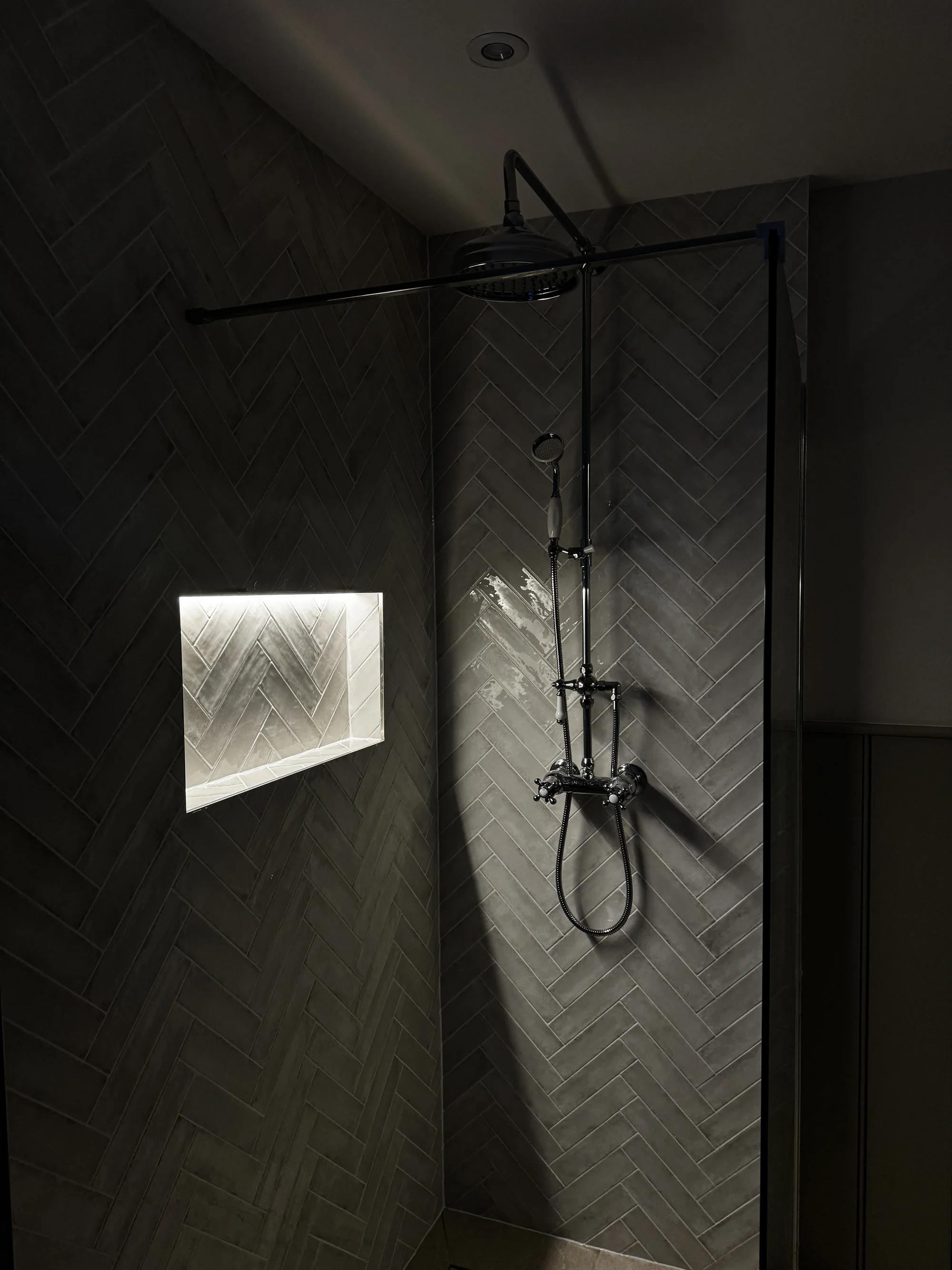 Lit shower niche set into the herringbone tiling
