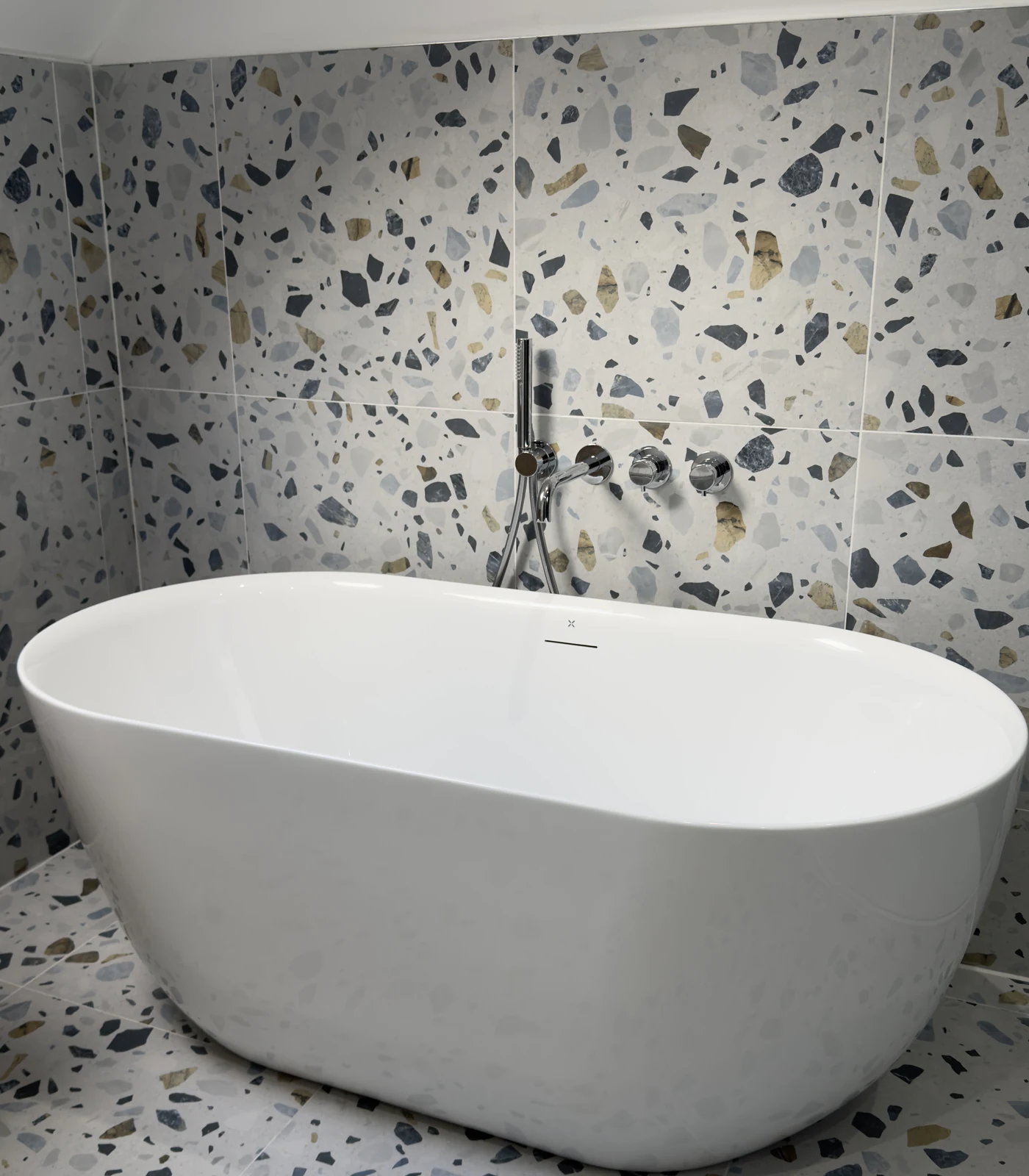 Freestanding bath against terrazzo tiling in a family bathroom renovation, Letchworth Garden City