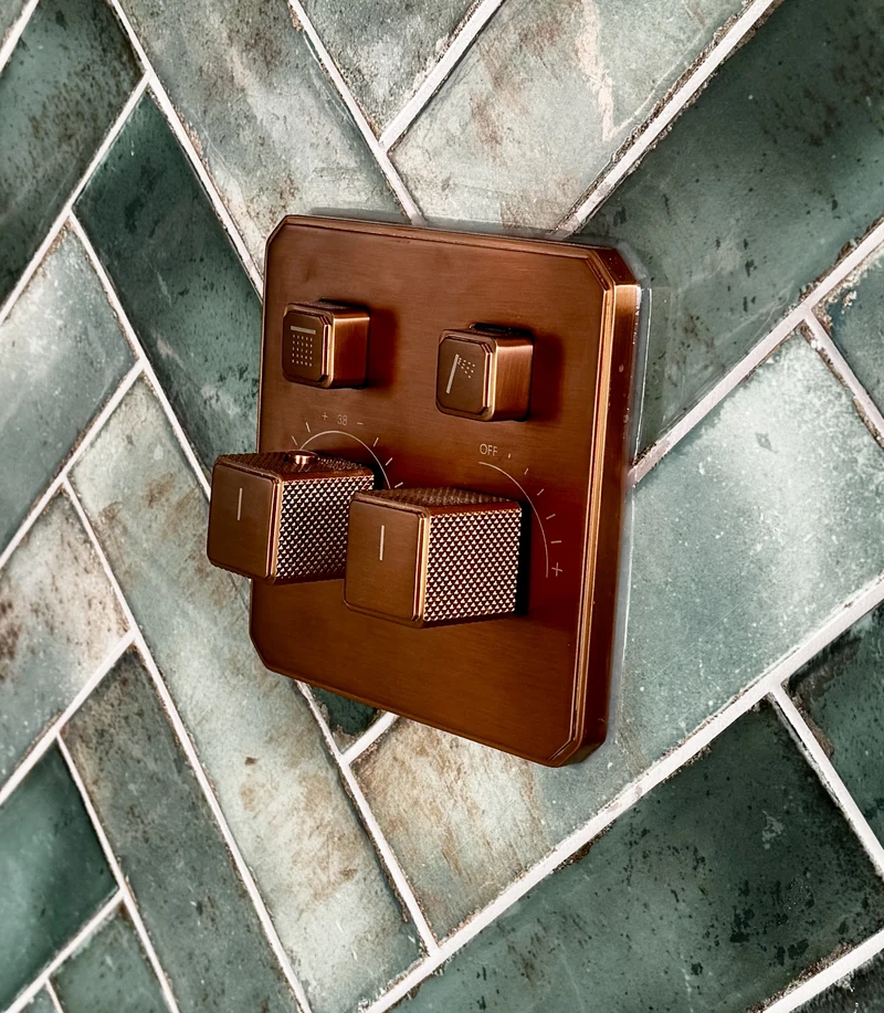 Antique copper shower controls on green herringbone tiling, St Albans