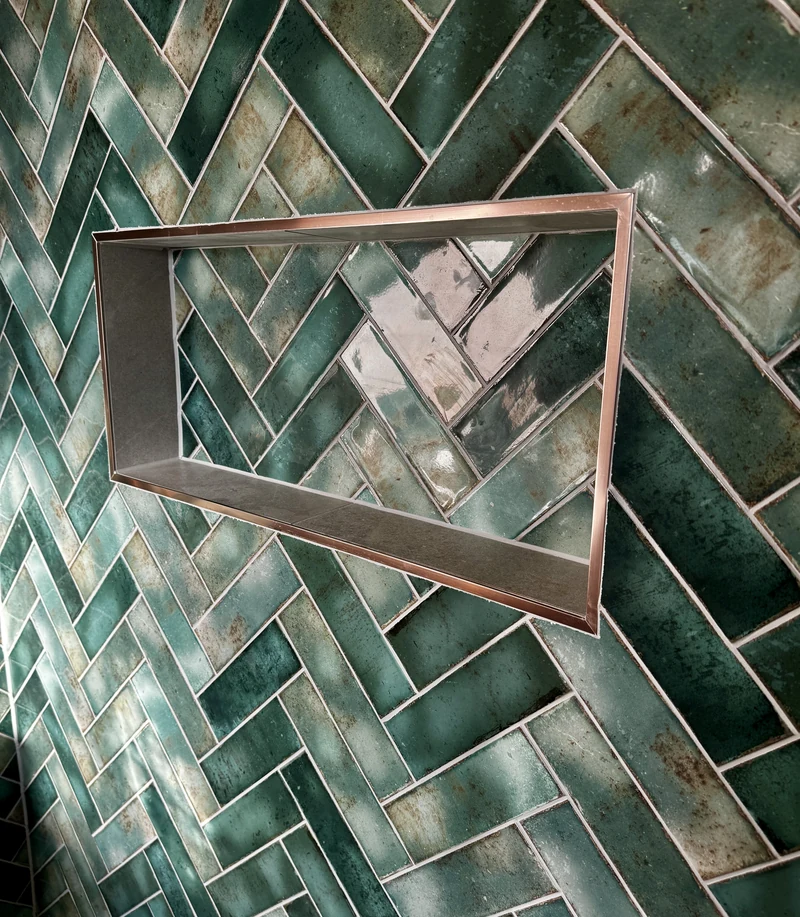 Copper-framed shelf niche set into green herringbone tiling, en suite renovation St Albans