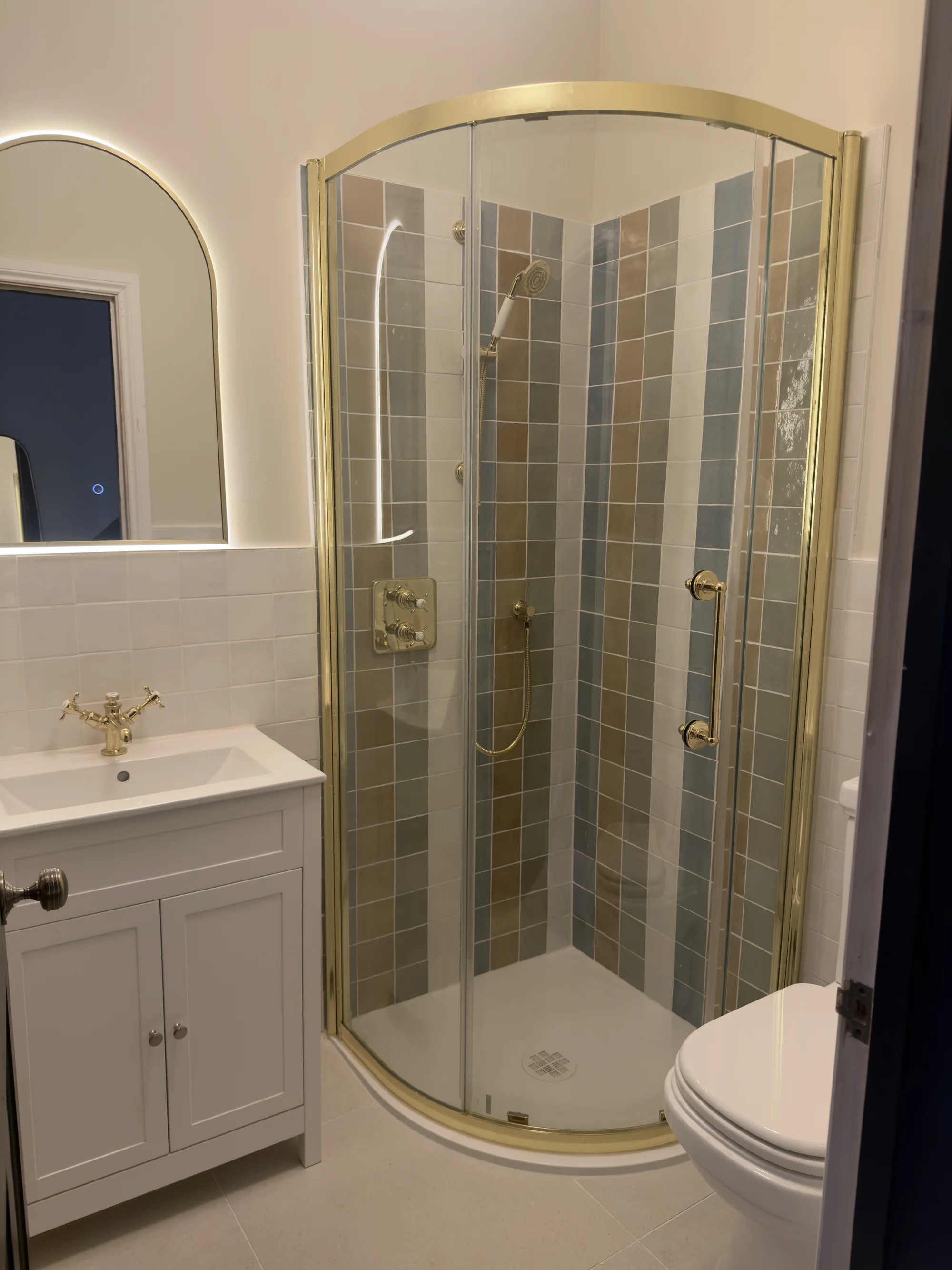Bathroom installation with a brass-framed quadrant shower and shaker vanity