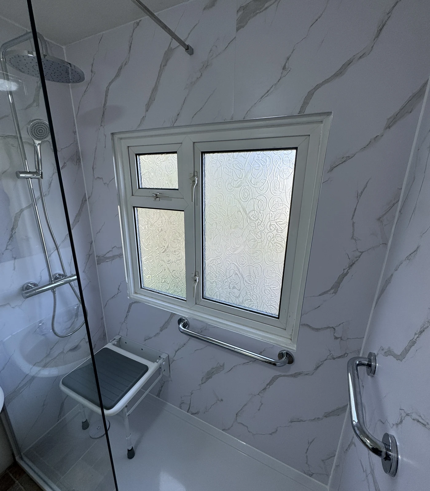 Level-access shower with fold-down seat and grab rails, accessible bathroom Hertfordshire