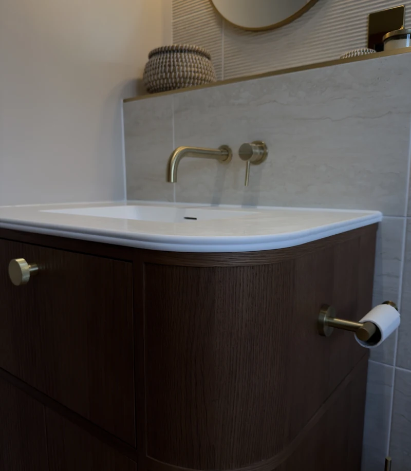Wall-mounted brass taps over the curved countertop basin